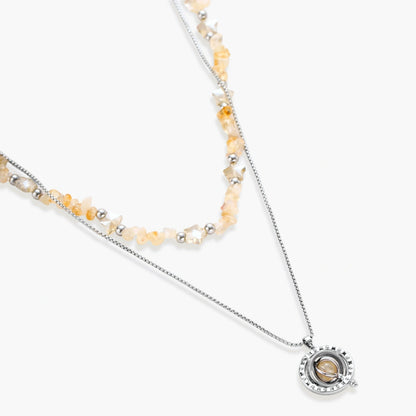Two-layer necklace with natural stone chips and eco-brass beads, featuring a circular wrapped pendant on cream background.