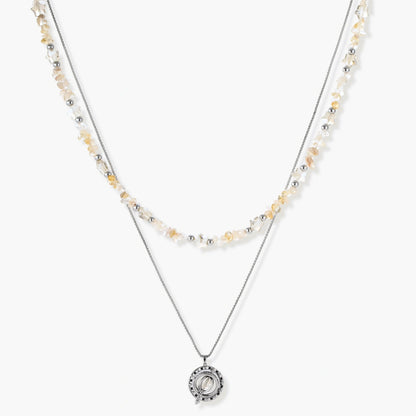 Two-layer necklace with natural stone chips and eco-brass beads, featuring a circular wrapped pendant on cream background.