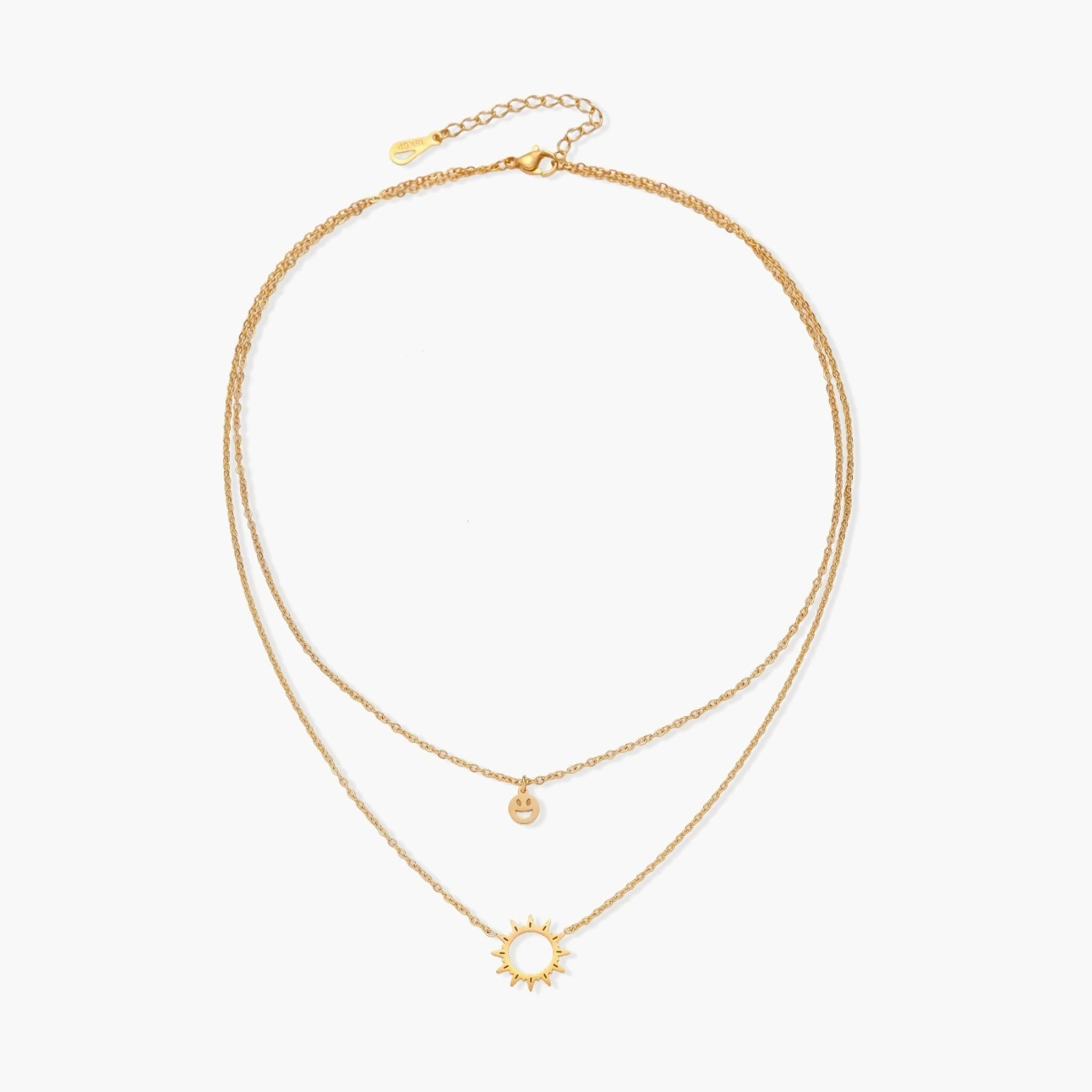 Gold layered necklace set with sunburst and smiley face pendants on delicate chains against white background.