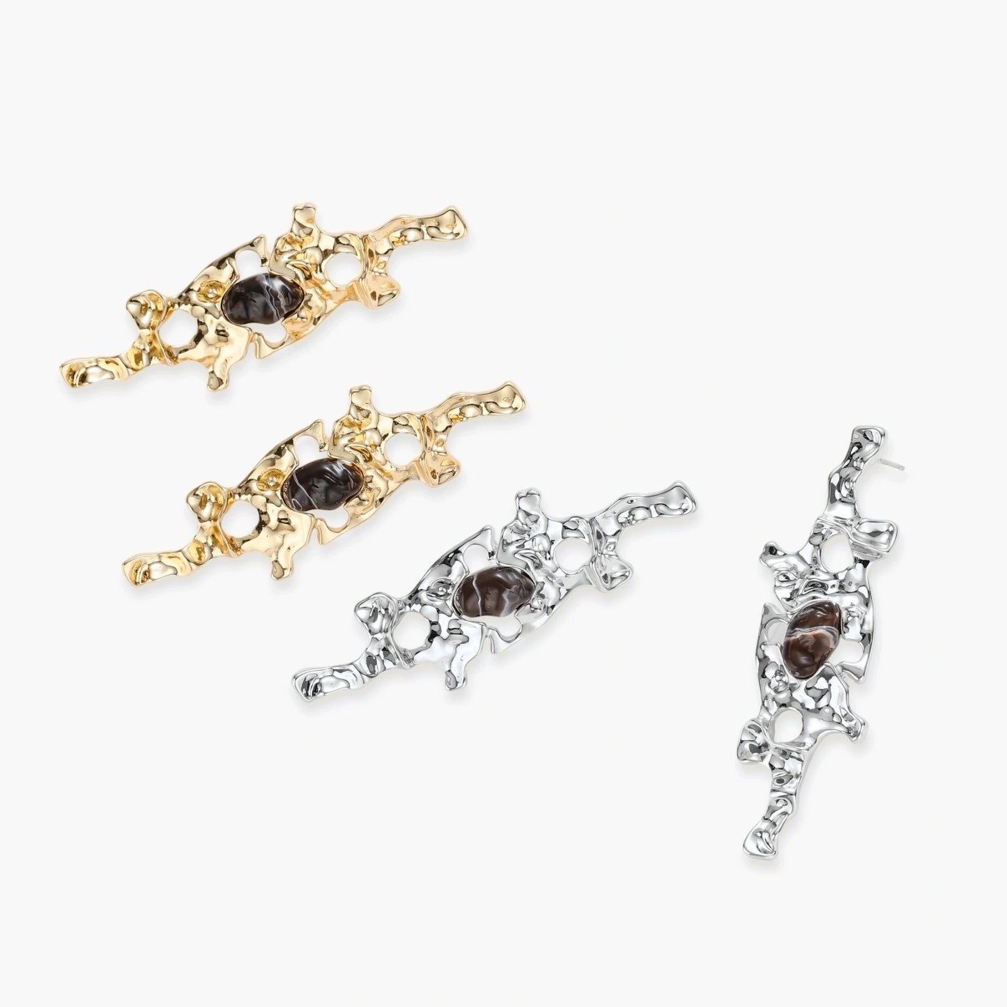 Gold-toned abstract dangle earrings with flowing cutout design and dark resin center accents on white background.