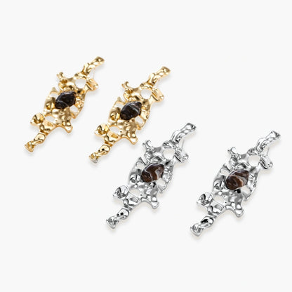Gold-toned abstract dangle earrings with flowing cutout design and dark resin center accents on white background.