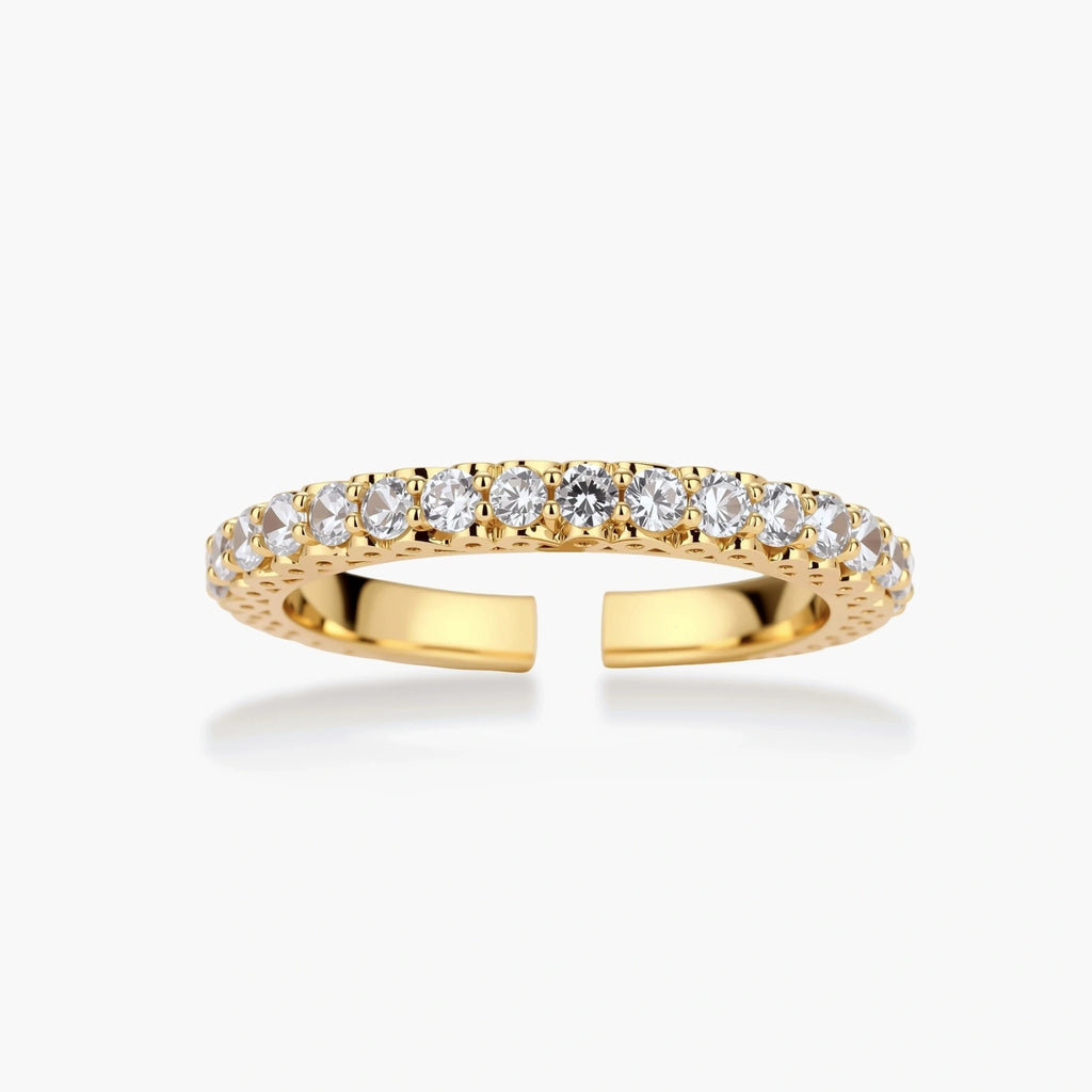 Close-up of adjustable gold-plated ring with continuous row of round zirconia stones on neutral background.